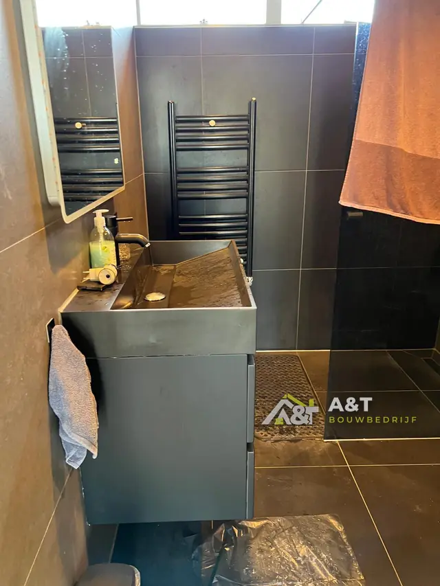 Badkamer in antraciet. Donkere tegels, een waskom in betonlook en een zwarte designradiator.