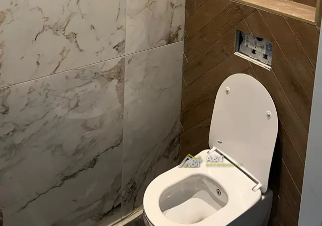 Toilet in marmer en visgraat. Hangtoilet tegen een wand in houtlook-visgraat, naast groot marmerlook.